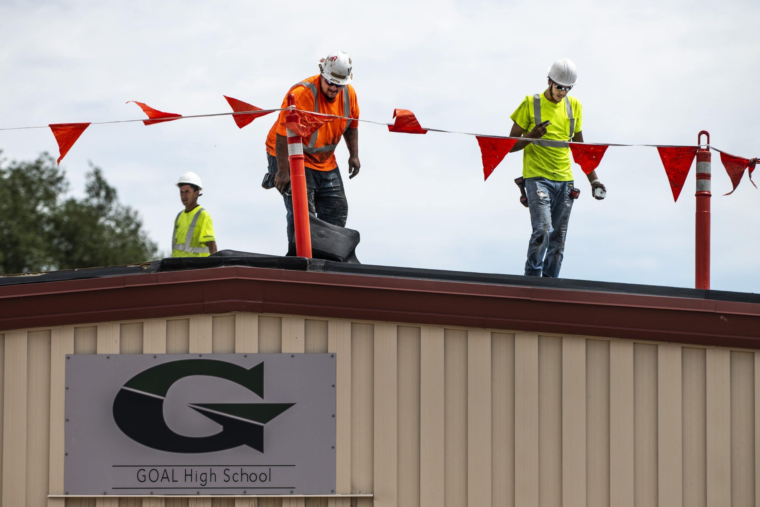 three men working on the Goal High School roof